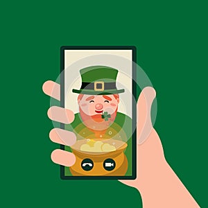 Online congratulations with Patricks day. Hand holding smartphone video player window with Leprechaun and pot.Video call