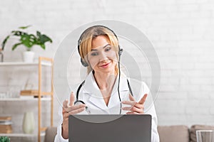 Online consultant at medical center. Friendly doctor gesticulate, looking at laptop, communicating with patient