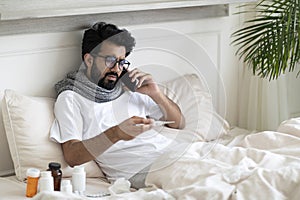 Online Consultation. Sick Indian Man Calling Doctor While Sitting In Bed