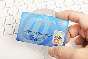 Online credit card payment - hand holding a credit card above a keyboard