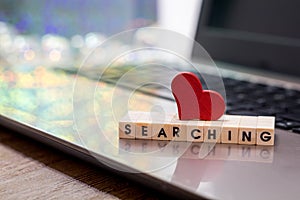 Online Dating concept with laptop red heart shape and wood word searching