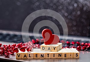 Online Dating concept with laptop and wood words VALENTINE`S DAY with black bokeh