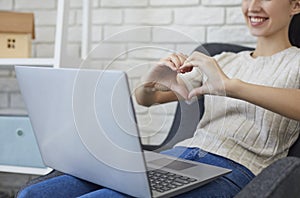 Online dating. Cropped view of young woman showing heart with hands to her boyfriend while talking online on laptop