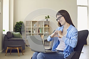 Online dating. Happy young woman talking to her boyfriend on laptop. Loving girl showing heart with hands to pc screen