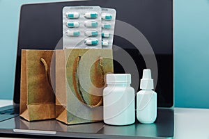 Online delivery and shopping concept. Paper bags with prescription drugs and pills and white conteiners on laptop