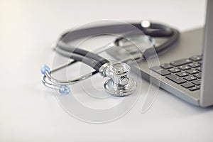 Online doctor call concept. Telemedicine. Stethoscope and laptop on a white table.