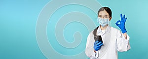 Online doctor and clinic. Young woman in medical face mask, using smartphone for client remote online appointment
