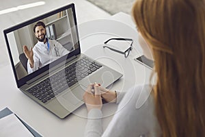 Online doctor consultation. Male doctor waving a hand from a laptop monitor video consultation for a girl patient