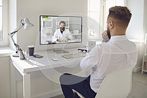 Online doctor.A man talking to a doctor online on a computer on a desk in an office. Online medical consultation.