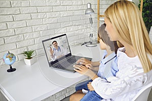 Online doctor. Patient Mother with a child has a video call consultation to a doctor therapist sitting at a table in a