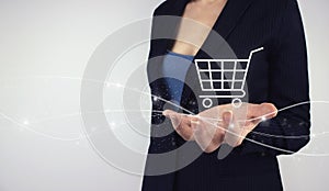 Online E-Commerce Shopping concept. Hand hold digital hologram Shopping cart on grey background. Digital Marketing Online, e-