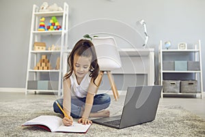 Online education of children. A little girl does a teacher lesson from a video lesson a distance learning web conference