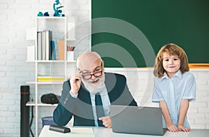 Online education. Old teacher and pupil in school. Schoolboy in classroom with laptop.