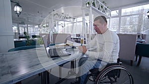 Online education, student disabled man on wheelchair uses modern laptop technology to learn from online lessons and