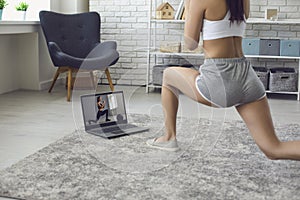 Online fitness at home. The girl does exercises watching the video course the trainer has a laptop at home.