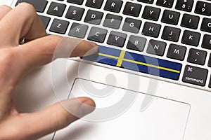 Online International Business concept: Computer key with the Sweden on it. Male hand pressing computer key with Sweden