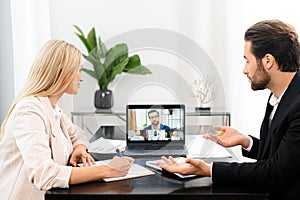 Online interview concept. Side view of the male and female is having online video meeting with pleasant colleagues on a