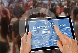 Online job hunting Hands with computer tablet reading employment ads infront of crowd of people