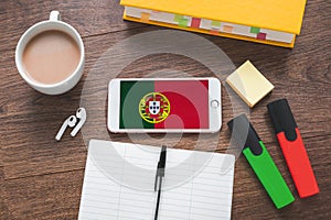 online learning a foreign Portuguese language, cup of coffee, notebook, pen, textbook, smartphone