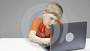 Online learning in front of a laptop a child sits and diligently types on a laptop keyboard