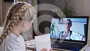 Online learning, girl studying mathematics sitting at laptop and listens to her female teacher from home in coronavirus