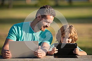 Online learning. Happy father using laptop relax with schooler son holding laptop have fun together, smiling dad and