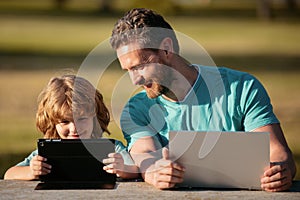 Online learning. Happy father using laptop relax with schooler son holding laptop have fun together, smiling dad and