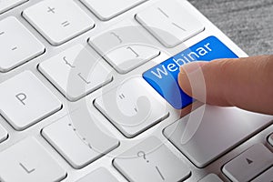 Online learning. Woman pressing button on computer keyboard with word Webinar, closeup