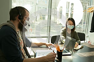 An online lesson during quarantine. Young teachersin medical masks conduct an online lesson