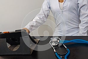 Online medical consultation - doctor working on tablet in clinic office