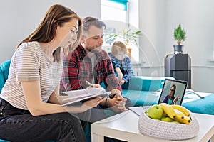 Online medical consultation, family sitting at home on sofa in living room with laptop
