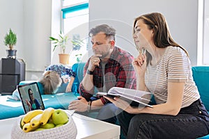 Online medical consultation, family sitting at home on sofa in living room with laptop