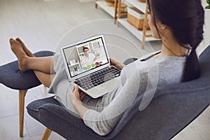 Online medical consultation..A sick young woman video chat with a male doctor sitting at home. photo