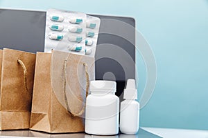 Online medical shopping concept. Paper bags with prescription drugs and pills and conteiners on laptop