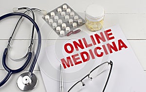 ONLINE MEDICINA word on paper with stethoscope and pills photo