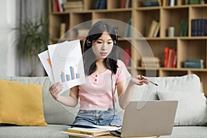 Online meeting. Young japanese female manager demonstrating financial report to colleagues, talking to webcamera