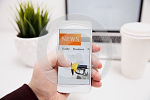 Online news in mobile phone. Close up of smartphone screen. Man reading articles in application. Hand holding smart