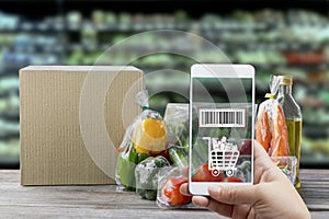 Online order grocery shopping on touch screen concept. Hand holding smart phone with checks the bar code on packaging fresh