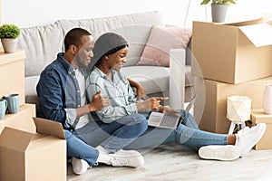 Online Order. Young black couple using laptop, purchasing furniture in internet