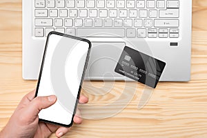 Online paying shopping, electronic payment with credit card, cell phone mockup, laptop over wooden table background, close up