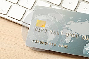 Online payment concept. Bank card and computer keyboard on wooden table, closeup