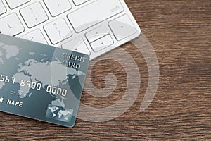 Online payment concept. Bank card and computer keyboard on wooden table, top view. Space for text