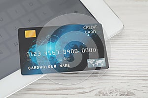 Online payment concept. Bank card and tablet on white wooden table, closeup