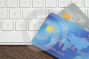 Online payment concept. Bank cards and computer keyboard on wooden table, closeup