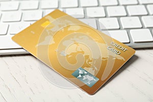 Online payment. Credit card and keyboard on white wooden table, closeup