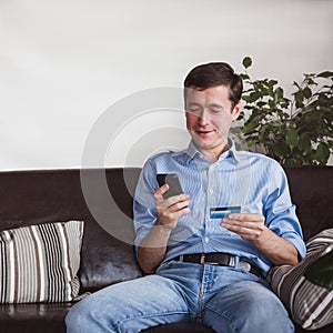 Online payment. Man holding a credit card and using smart phone for internet shopping. Sale in the online store