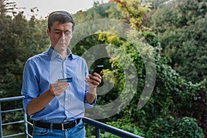 Online payment. Man holding a credit card and using smart phone for internet shopping. Sale in the online store