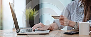 Online payment,woman`s hands holding a credit card and using laptop computer for online shopping with vintage filter tone