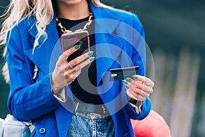 Online payment. Woman& x27;s hands holding a credit card and using smart phone for online shopping.