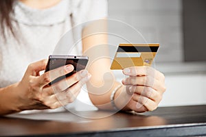 Online payment, women`s hands holding a credit card and using smart phone for online shopping